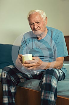 Senior Man Sitting On Bed Suffering From Depression