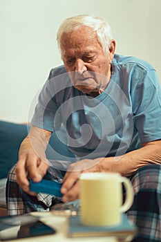 Senior Man Sitting On Bed Taking Medication
