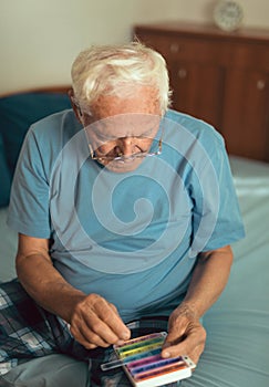 Senior Man Sitting On Bed Taking Medication