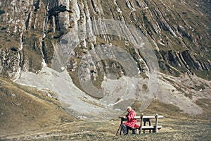 Senior man is sitting on the bench in the mountain