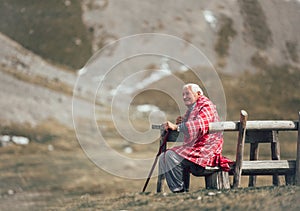 Senior man is sitting on the bench in the mountain