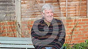 Senior man sitting on a bench and waving.