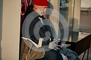 Senior man sitting in the center of city asking for money
