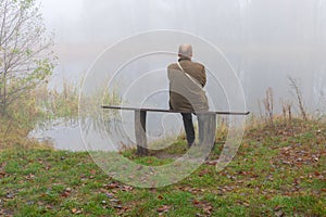Senior man sitting lonely on a bench on riverside