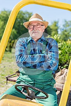 Senior man sitting proud in his tractor after cultivating his farm