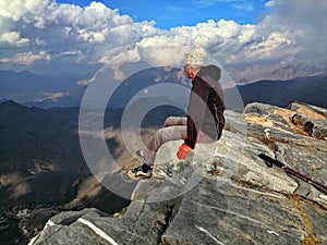 Senior man sitting on the rock at the edge of canyon