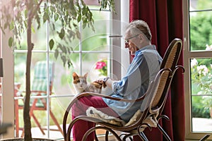 Senior man sitting in a rocking chair with his cat in his lap