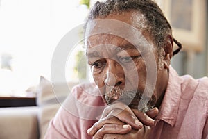 Senior Man Sitting On Sofa At Home Suffering From Depression