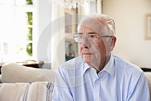 Senior Man Sitting On Sofa At Home Suffering From Depression