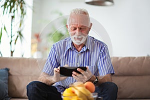 Senior man sitting on sofa and using digital tablet
