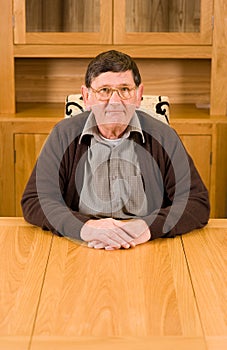 Senior man sitting at table with copyspace below