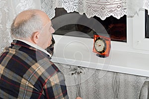 Senior man sitting waiting at night with a clock