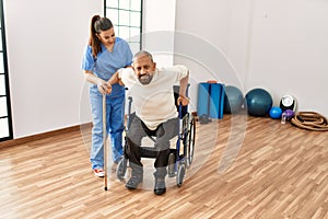 Senior man sitting on wheelchair being assited by geriatric nurse