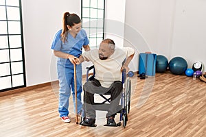 Senior man sitting on wheelchair being assited by geriatric nurse