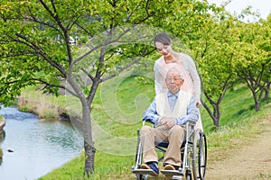 Senior man sitting on a wheelchair with caregiver