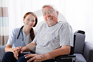 Senior Man Sitting On Wheelchair With Female Nurse