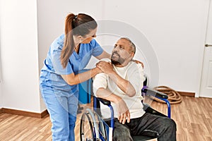Senior man sitting on wheelchair and geriatric nurse at rehabilitation clinic