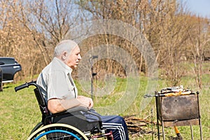 Senior Man Sitting on Wheelchair Grilling Outside