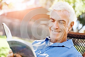 Senior man sittingin park while reading book photo