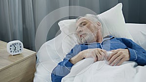 Senior man sleeping in bed in the morning, healthy rest during recovery time