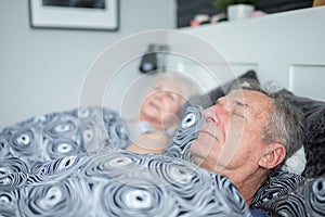 Senior man sleeping in comfortable bed with wife