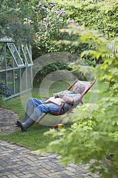 Senior Man Sleeping On Deckchair In Backyard