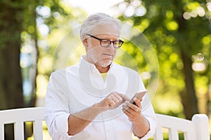 Senior man with smartphone at summer park
