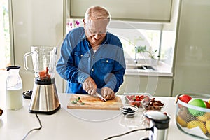 Senior man smiling confident cutting datil at kitchen