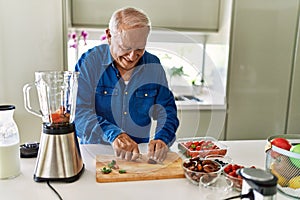 Senior man smiling confident cutting datil at kitchen photo