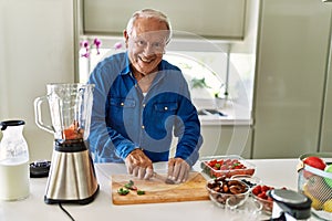 Senior man smiling confident cutting datil at kitchen photo
