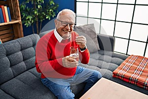 Senior man smiling confident taking pill at home