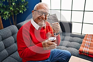 Senior man smiling confident taking pill at home