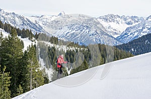 Senior man is snowshoe hiking in alpine snow winter mountains. Allgau, Bavaria, Germany.