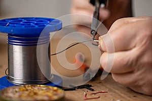 Senior man soldering a wires, repairing an electronic