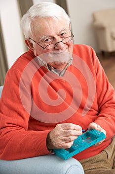 Senior Man Sorting Medication Using Organiser photo