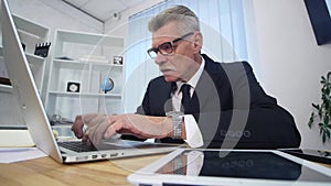 Senior man speaks with white smartphone in office