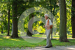 Senior man spending free time outdoors in nature, watching forest animals through binoculars.