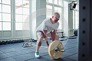 Senior man in sportswear weightlifting alone in a gym