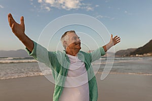 Senior man standing with arms outstretched on the beach