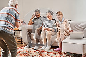 Senior man standing in front of his friends and showing something without words