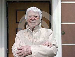 Senior man standing in front of a house door
