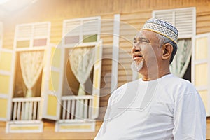 Senior man standing in front of wooden house