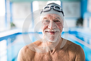 Senior man standing in an indoor swimming pool.