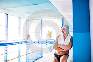 Senior man standing in an indoor swimming pool.