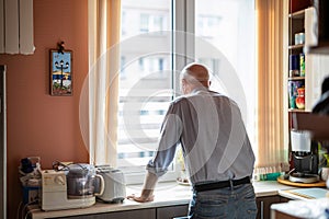 Senior man standing at the kitchen counter in his house