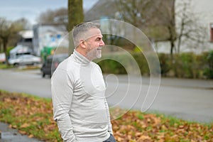 Senior man standing loking off to the side in a street