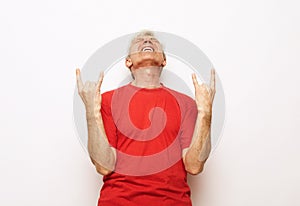 Senior man standing over isolated white background shouting with crazy expression doing rock symbol with hands up.
