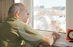 Senior man standing reminiscing at a window