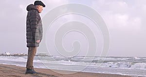 A senior man standing by the stormy sea in winter time