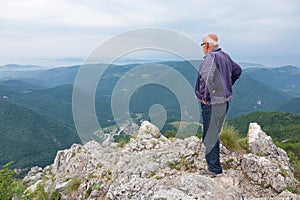 Senior man standing on top of a mountain